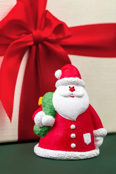Nahaufnahme Foto von Gips bunten Weihnachtsmann auf der Geschenkbox über grünem Hintergrund. — Stockfoto
