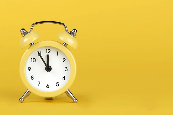 Sarı zemin üzerinde sarı yuvarlak alarm saati.