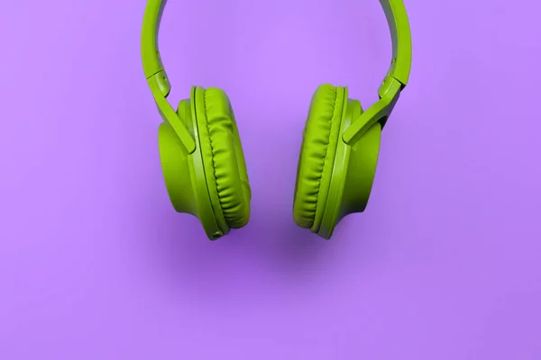 Mor arka planda izole edilmiş modern yeşil cyan kulaklıklar.