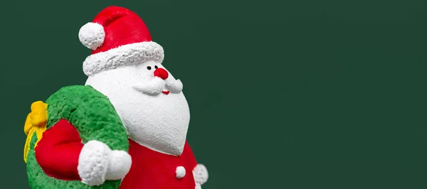 Breites Foto von Gips bunten Weihnachtsmann isoliert über grünem Hintergrund. Neujahrs- und Weihnachtskonzept. — Stockfoto