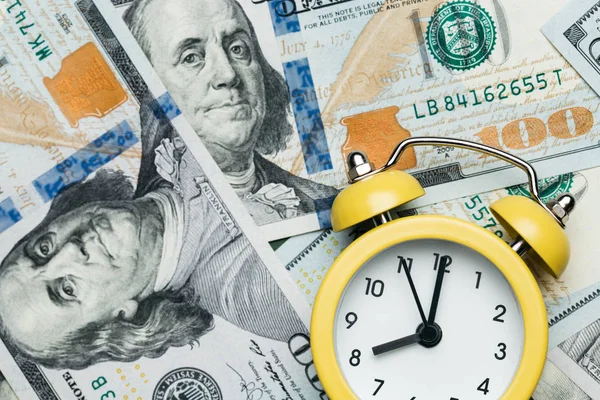 100 미국 달러 지폐 더미 위에 있는 노란 알람 시계입니다. 대출, 대출금 및 저당 개념. — 스톡 사진