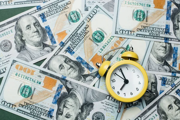 100 미국 달러 지폐 더미 위에 있는 노란 알람 시계입니다. 대출, 대출금 및 저당 개념. — 스톡 사진