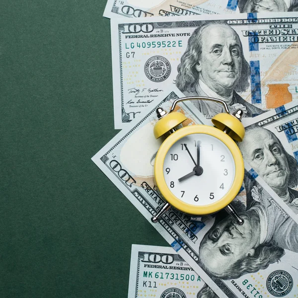Sárga ébresztőóra egy halom száz dolláros bankjegyen. Hitel-, betét- és jelzáloghitel-koncepció. — Stock Fotó
