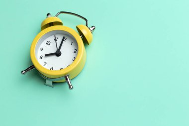 Cyan arka planda sarı yuvarlak alarm saati.