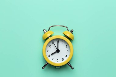 Cyan arka planda sarı yuvarlak alarm saati.