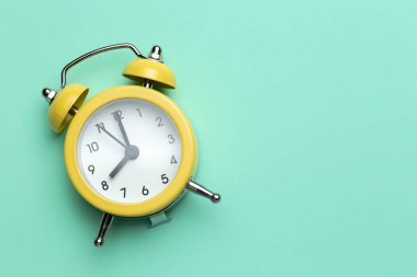 Cyan arka planda sarı yuvarlak alarm saati.