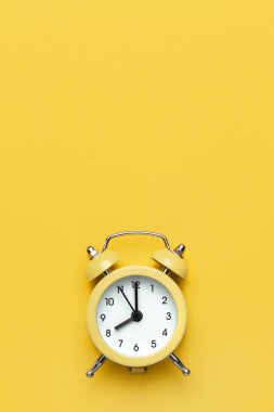 Sarı zemin üzerinde sarı yuvarlak alarm saati.