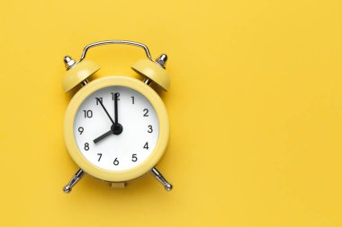 Sarı zemin üzerinde sarı yuvarlak alarm saati.