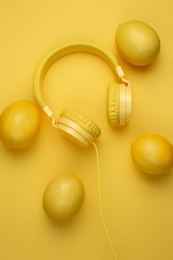 Sarı arka planda limonlarla süslenmiş sarı kulaklıklar. Müzik konsepti.