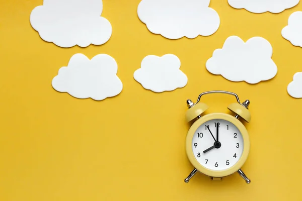 Yellow round alarm clock and white clouds on the yellow background. — Stock Photo, Image