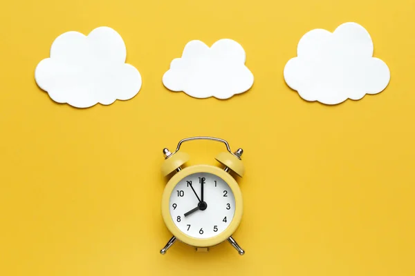 Yellow round alarm clock and white clouds on the yellow background. — Stock Photo, Image