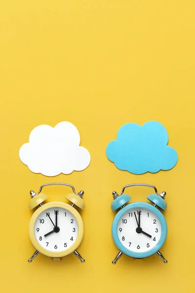 Sarı ve mavi iki yuvarlak alarm saati ve sarı arka planda bulutlar.. — Stok fotoğraf