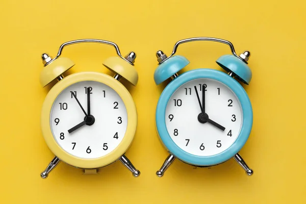 Dos relojes de alarma redondos amarillo y azul sobre el fondo amarillo . —  Fotos de Stock