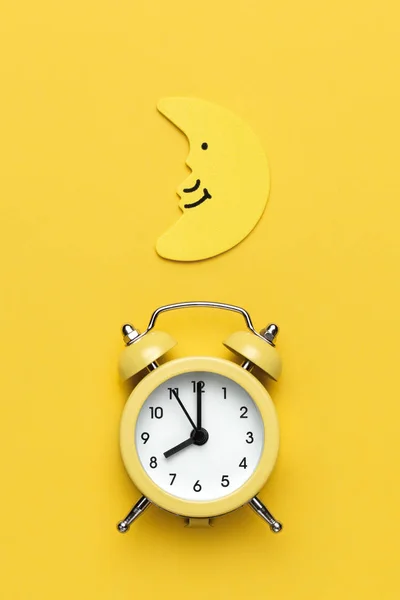 Reloj despertador redondo amarillo y luna en el fondo amarillo . —  Fotos de Stock
