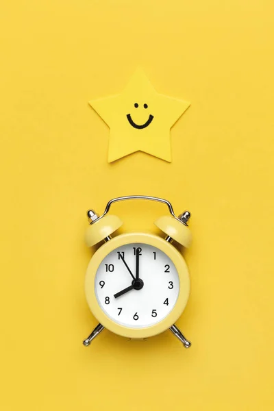 黄色の丸い目覚まし時計と黄色の背景の星. — ストック写真