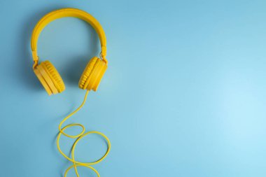 Mavi arka planda sarı kulaklıklar. Müzik konsepti.