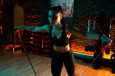 Alımlı genç bayan spor salonu bantlarıyla çalışıyor..