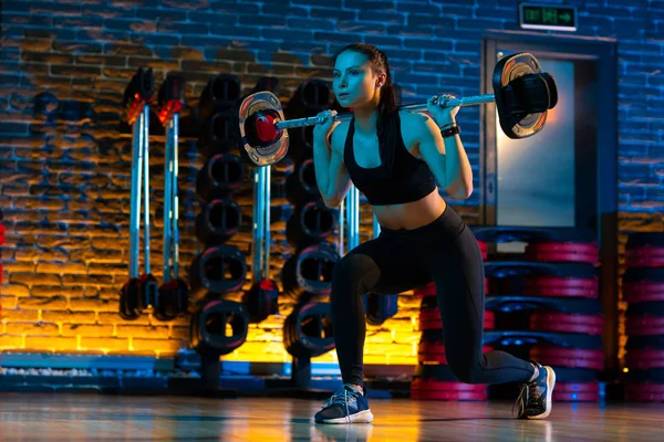 Mujer joven deportiva hacer ejercicios para las piernas y el culo con barra en el gimnasio. Concepto Salud y Deporte . — Foto de Stock