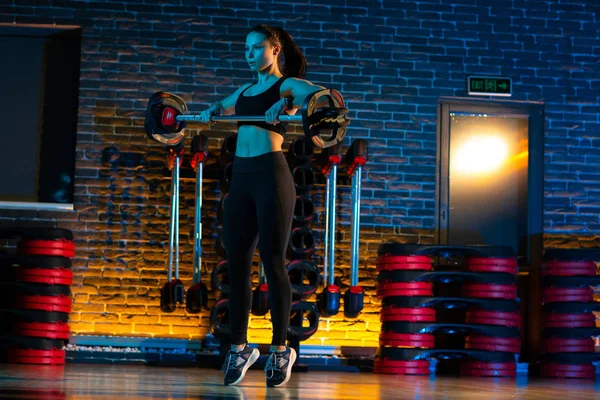 Tiro de mujer joven y saludable hacer ejercicios con barra de pesas en el gimnasio. Concepto Salud y Deporte . — Foto de Stock