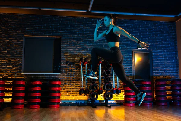 Sporty young attractive woman doing jump aerobic exercises in gym. — Stock Photo, Image