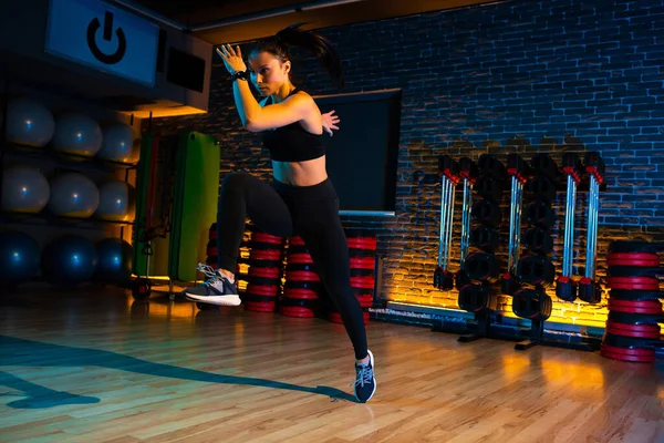 Sporty young attractive woman doing jump aerobic exercises in gym. — 스톡 사진