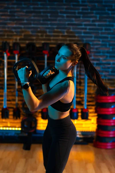 Mujer joven deportiva haciendo ejercicios de boxeo con placas de peso en el gimnasio . — Foto de Stock