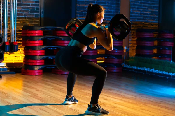 Tiro completo de mujer joven deportiva hacer ejercicio en cuclillas con barra en el gimnasio. Concepto Salud y Deporte. Vista trasera . — Foto de Stock