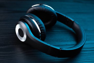 Koyu ahşap arka planda siyah kulaklık. Neon ışıkta kablosuz kulaklık..