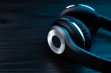 Koyu ahşap arka planda siyah kulaklık. Neon ışıkta kablosuz kulaklık..