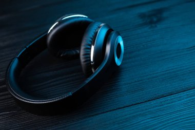 Koyu ahşap arka planda siyah kulaklık. Neon ışıkta kablosuz kulaklık..