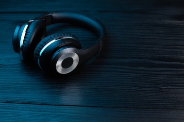 Koyu ahşap arka planda siyah kulaklık. Neon ışıkta kablosuz kulaklık..