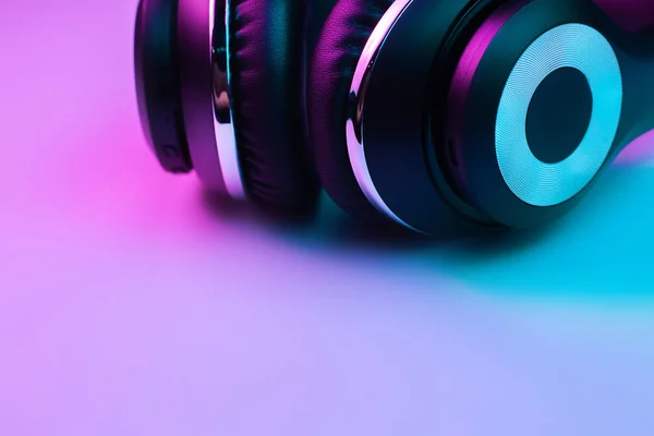 Foto de estilo retro 90s de auriculares inalámbricos negros con estilo en luces de neón . —  Fotos de Stock