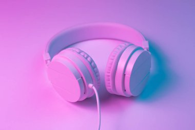 Beyaz kablosuz kulaklığın neon ışıklı Retro 90 tarzı fotoğrafı. Müzik konsepti.