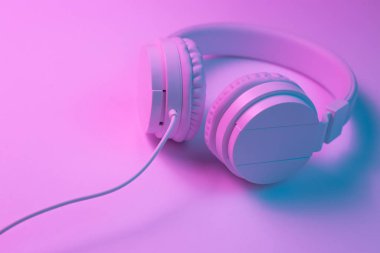 Beyaz kablosuz kulaklığın neon ışıklı Retro 90 tarzı fotoğrafı. Müzik konsepti.