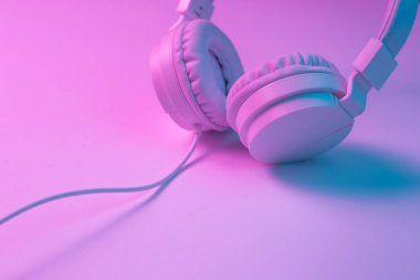 Beyaz kablosuz kulaklığın neon ışıklı Retro 90 tarzı fotoğrafı. Müzik konsepti.