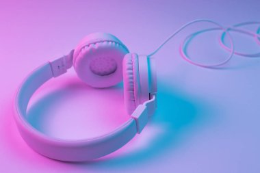 Beyaz kablosuz kulaklığın neon ışıklı Retro 90 tarzı fotoğrafı. Müzik konsepti.