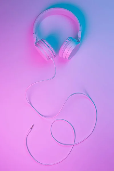 Beyaz kablosuz kulaklığın neon ışıklı Retro 90 tarzı fotoğrafı. Müzik konsepti. — Stok fotoğraf