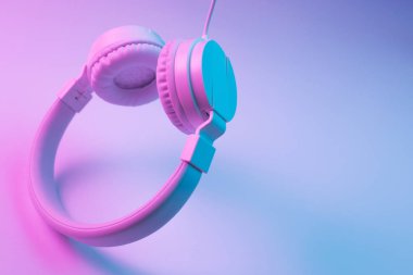 Beyaz kablosuz kulaklığın neon ışıklı Retro 90 tarzı fotoğrafı. Müzik konsepti.