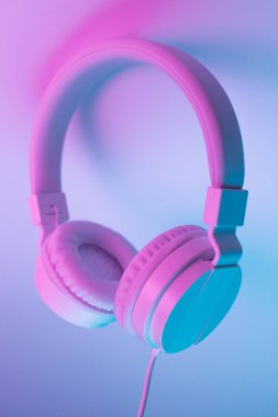 Beyaz kablosuz kulaklığın neon ışıklı Retro 90 tarzı fotoğrafı. Müzik konsepti.