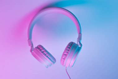 Beyaz kablosuz kulaklığın neon ışıklı Retro 90 tarzı fotoğrafı. Müzik konsepti.