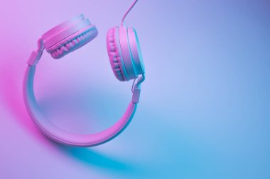 Beyaz kablosuz kulaklığın neon ışıklı Retro 90 tarzı fotoğrafı. Müzik konsepti.