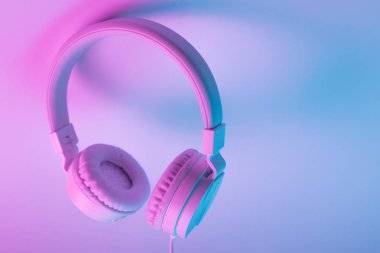 Beyaz kablosuz kulaklığın neon ışıklı Retro 90 tarzı fotoğrafı. Müzik konsepti.