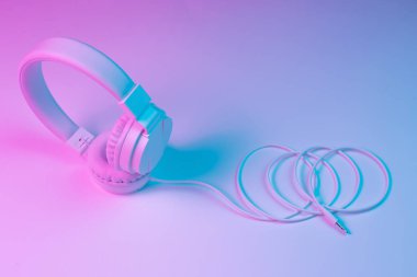 Beyaz kablosuz kulaklığın neon ışıklı Retro 90 tarzı fotoğrafı. Müzik konsepti.