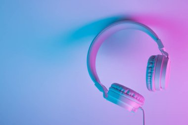 Beyaz kablosuz kulaklığın neon ışıklı Retro 90 tarzı fotoğrafı. Müzik konsepti.