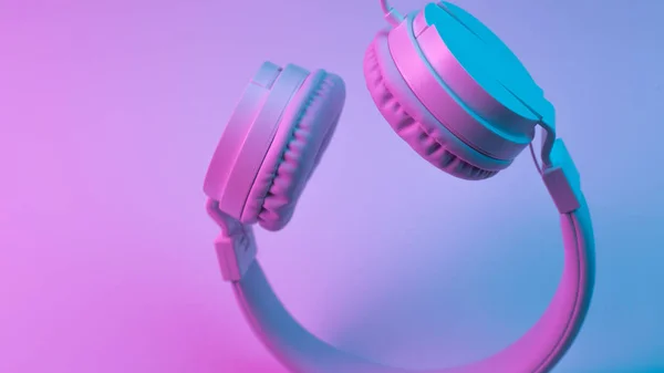 Foto in stile retrò anni '90 di eleganti cuffie wireless bianche in luci al neon. Concetto musicale . — Foto Stock