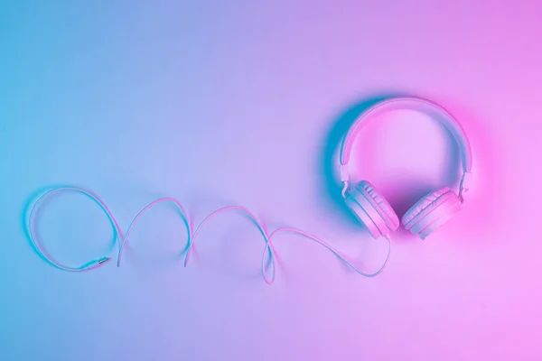 Beyaz kablosuz kulaklığın neon ışıklı Retro 90 tarzı fotoğrafı. Müzik konsepti. — Stok fotoğraf