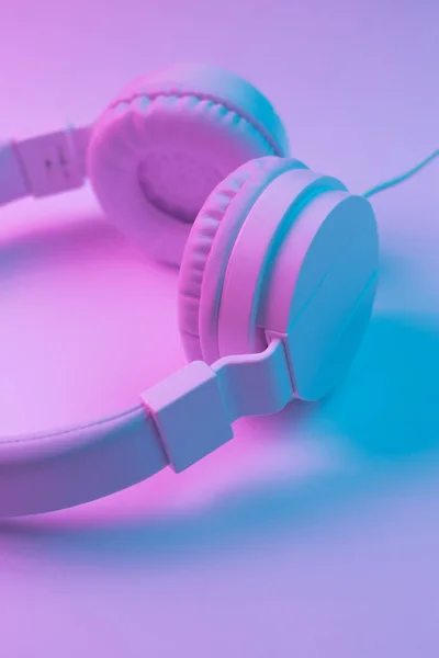 Retro 90s style photo of white stylish wireless headphone in neon lights. Music concept.