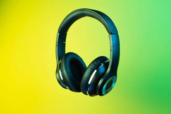 Retro 90s style photo of black stylish modern wireless headphone in neon lights over colorful background. — Stock Photo, Image