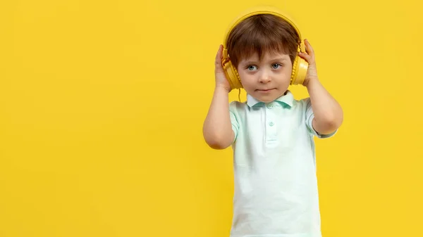 Lucu anak mendengarkan musik di headphone atas latar belakang kuning . — Stok Foto