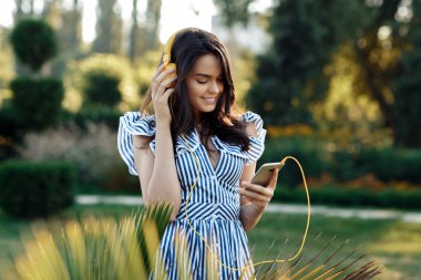 Parkta modern müzik dinleyen, kulaklıklı, şehvetli, esmer bir kadın..